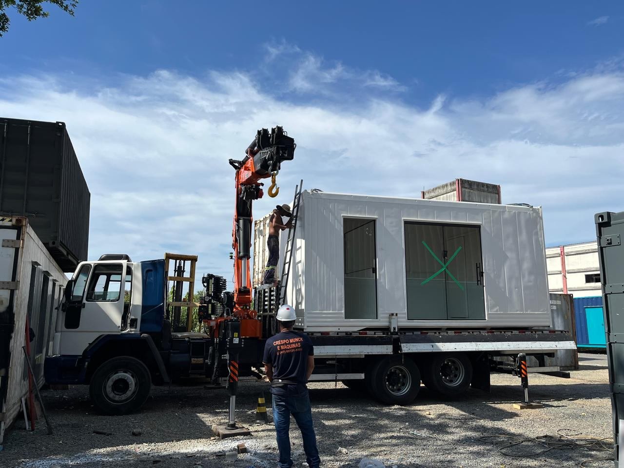 Caminhão guindaste içando estrutura elétrica no local da obra